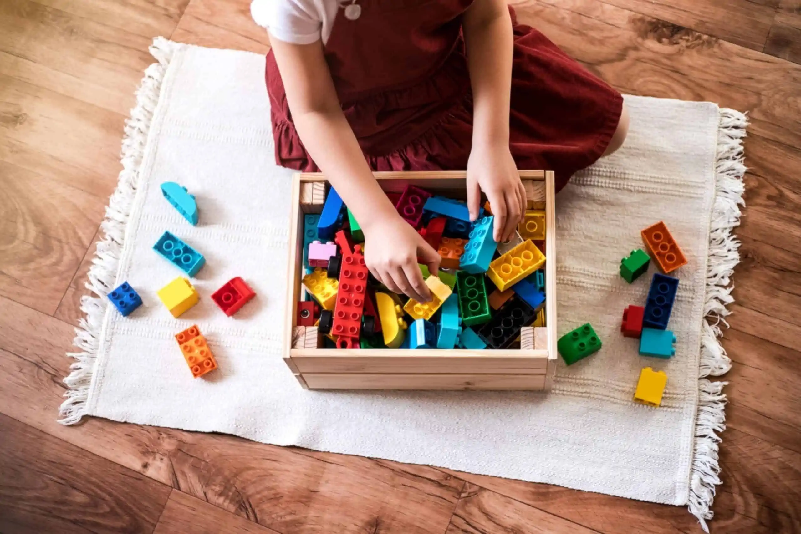 Little girl cleaning up the toy box at home