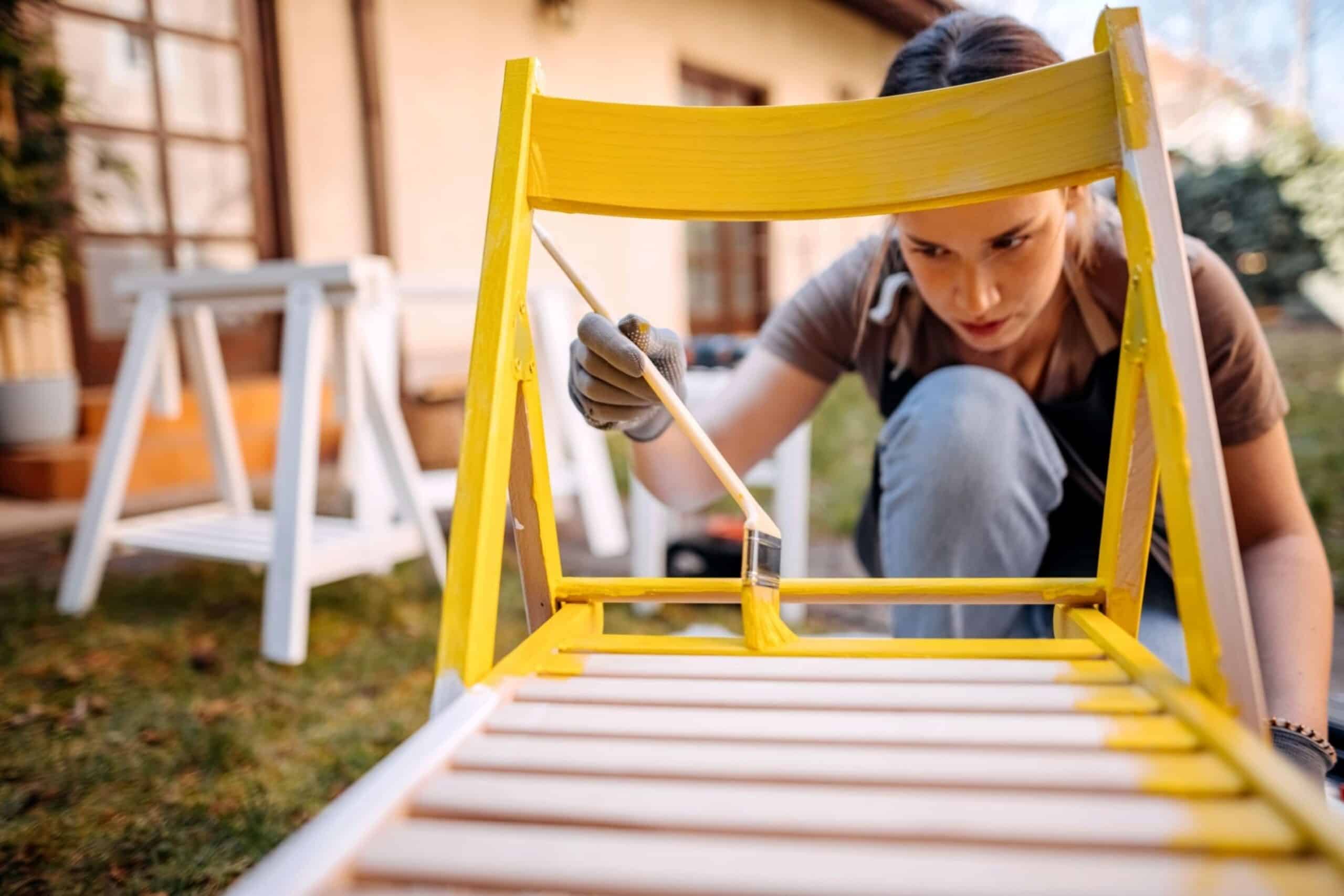 woman painting furniture in backyard of her home