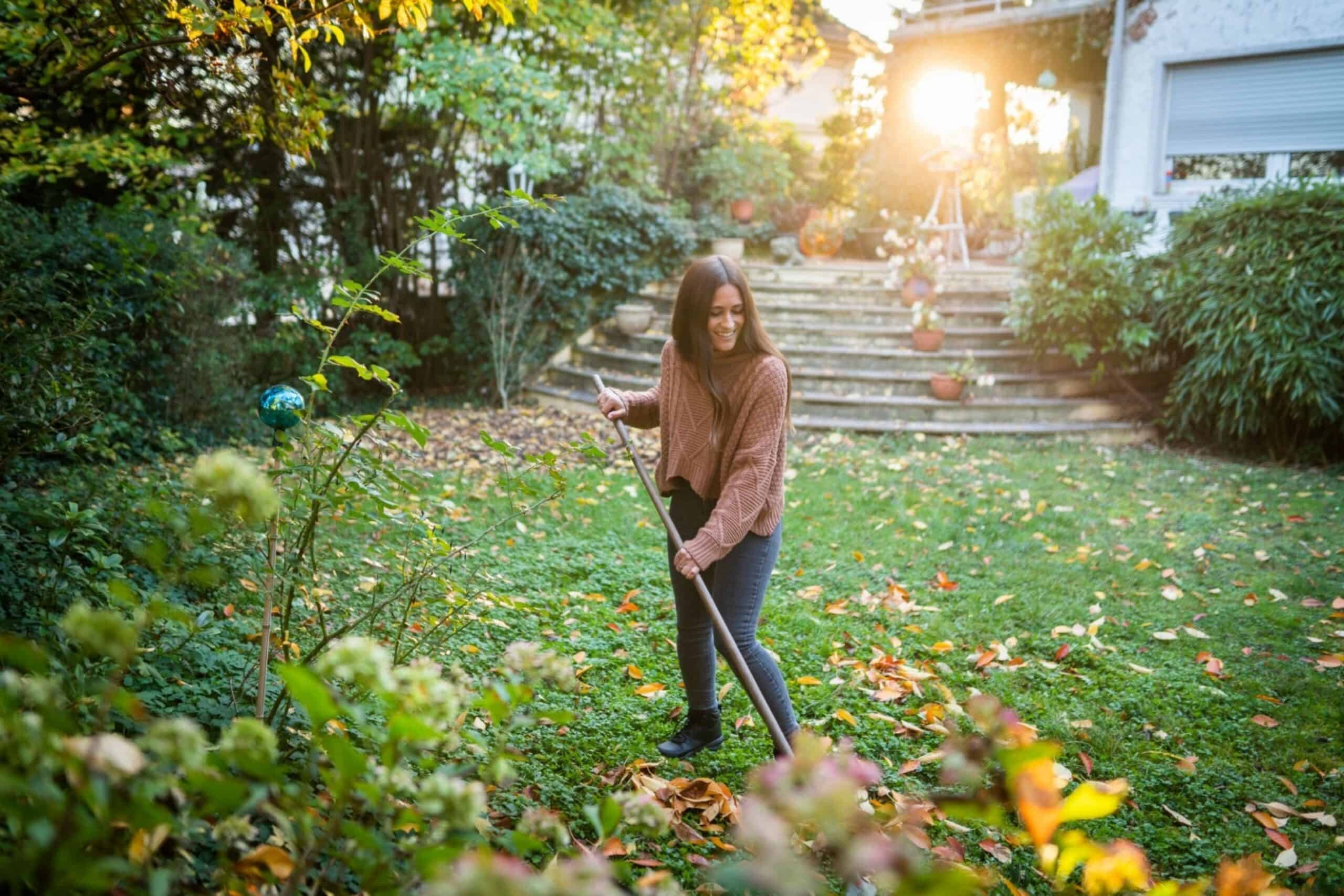  woman sweeping garden with broom in back yard