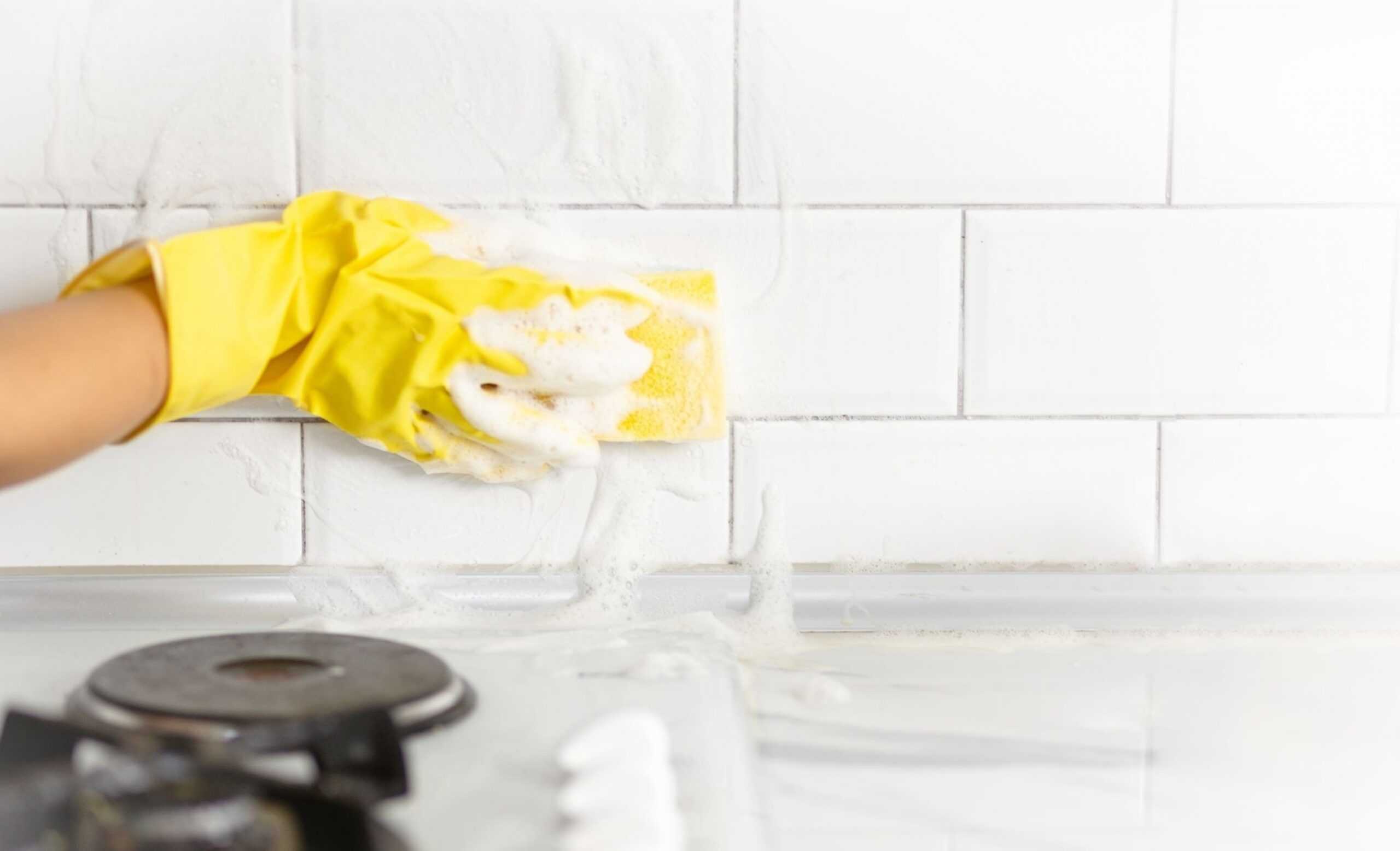 What is Oxybleach and How to Use It Tidyhere Image of Hand and Glove Cleaning the Kitchen Tiles