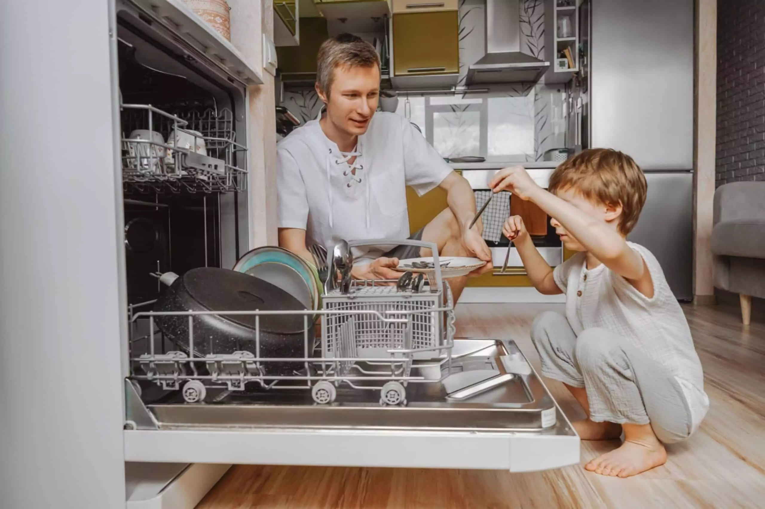 Dad and little son unloading the dishwasher. Home work together.