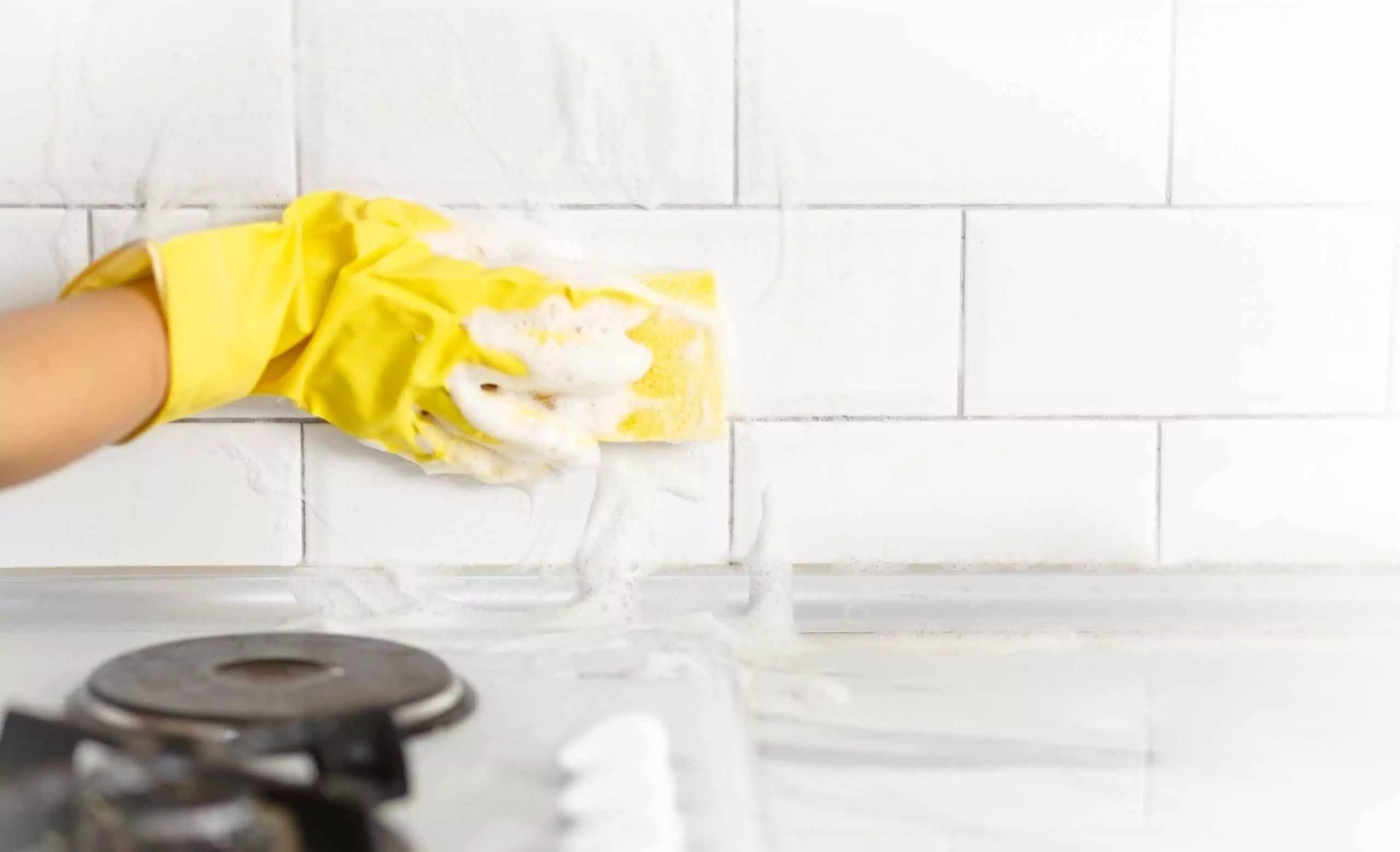 Hand and glove cleaning the kitchen tiles