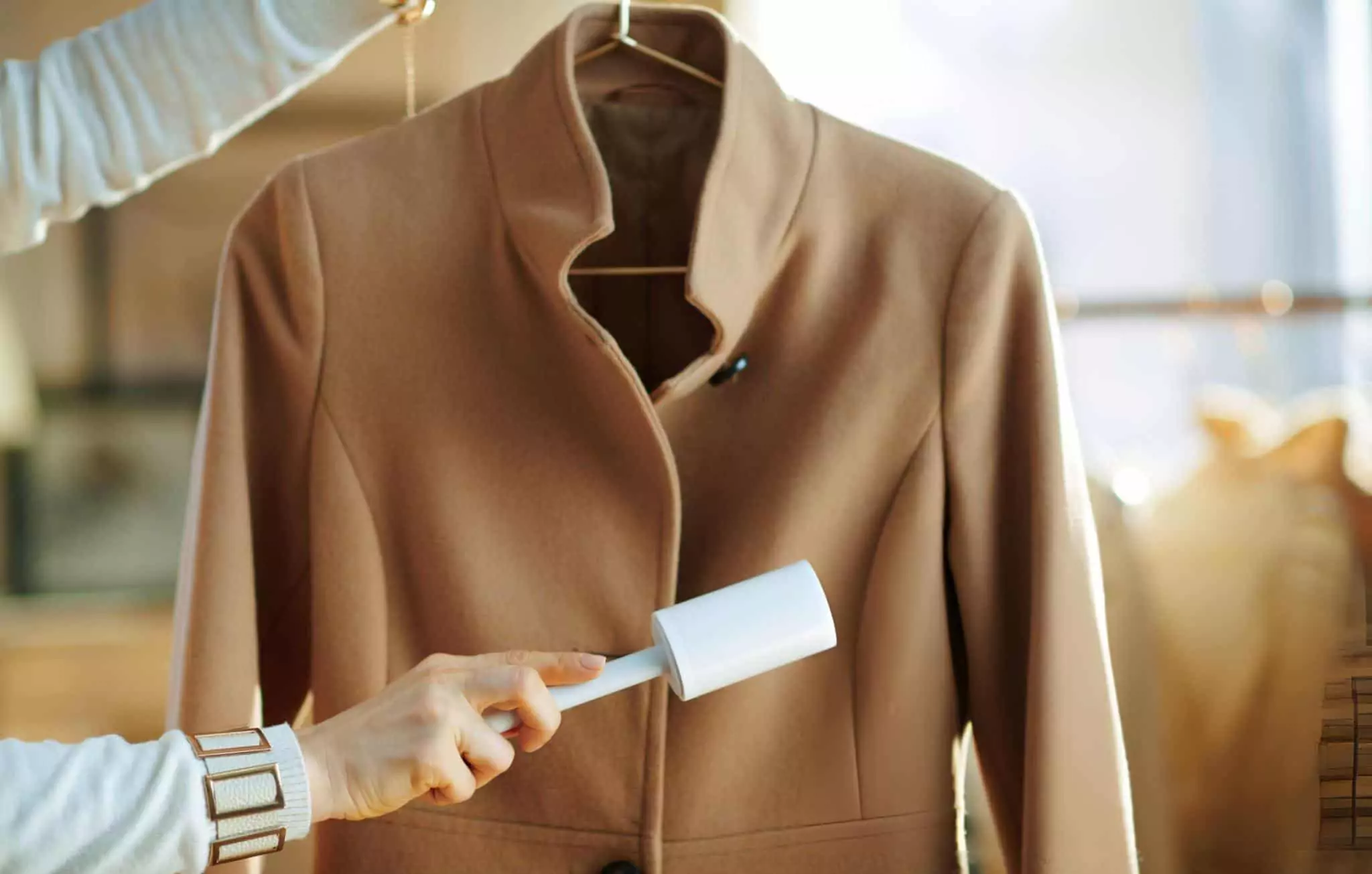 How to Remove Lint From Clothes Tidyhere Image of a Woman Cleaning Coat on Hanger with Lint Roller